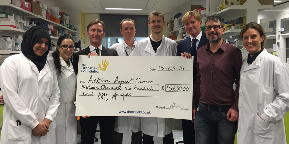 8 people in labcoats holding a giant cheque for AAC