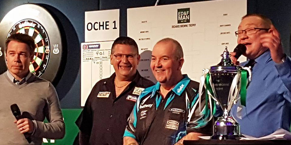 2 darts players on stage with trophy