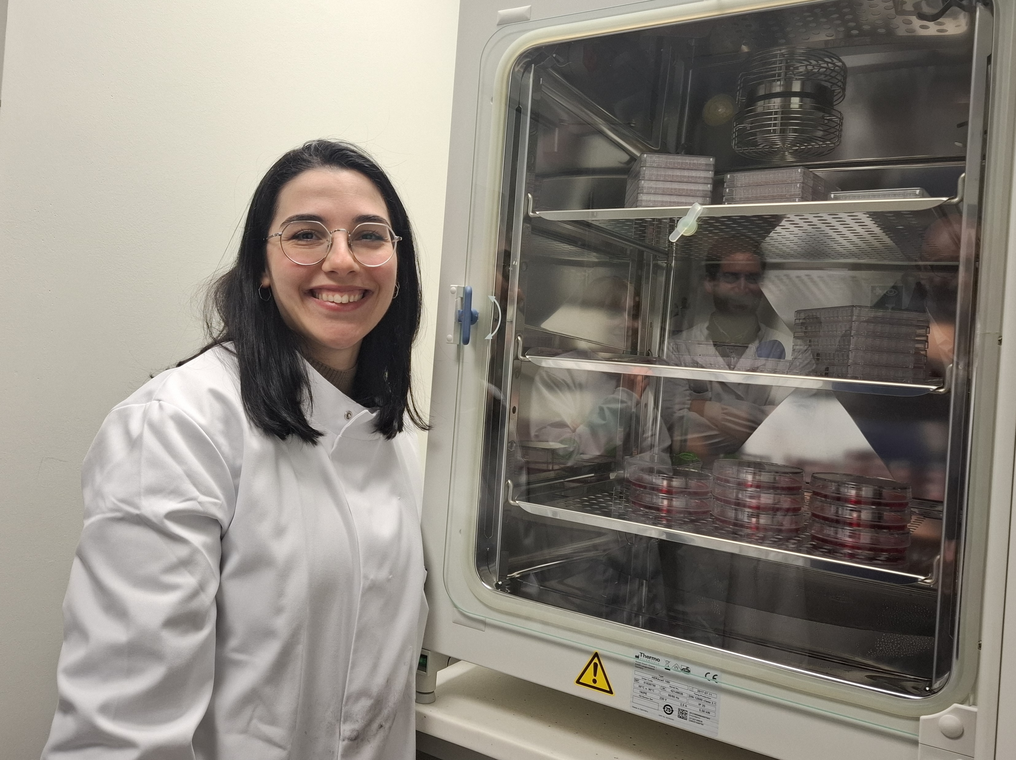 Lady in lab coat next to science fridge